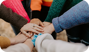 Hands in a huddle, symbolizing teamwork and community support for Mobile Overdose Prevention Site (MOPS).