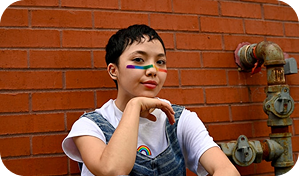 Person with rainbow face paint smiles, representing Pride and MOPS initiative.